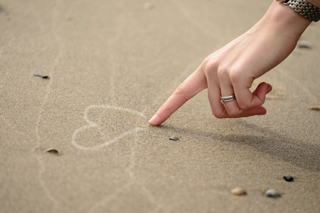 Selbstliebe Mantras für Mamas - Hand malt Herz in den Sand